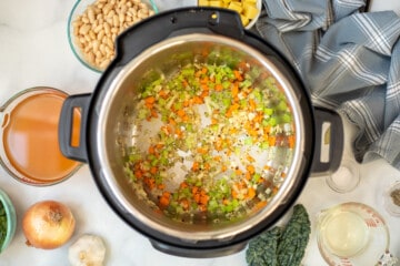 Carrots, onions, celery, garlic, and herbs sauteed in inner pot for White Bean and Kale Soup Recipe