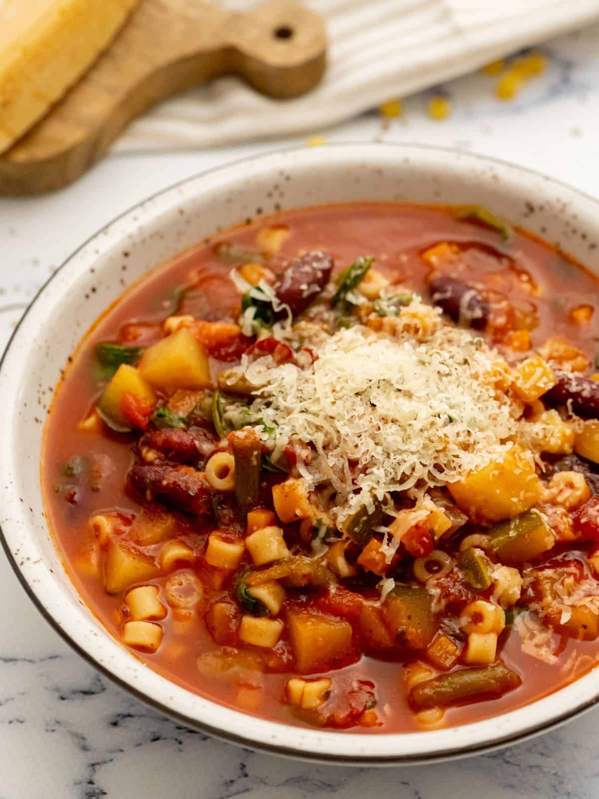 Bowl of slow cooker minestrone topped with parmesan cheese.