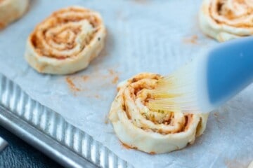 Brushing pizza rolls with infused olive oil.
