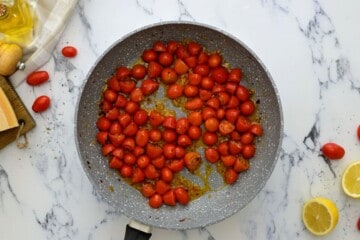 Halved grape tomatoes seared in saute pan with seasonings.