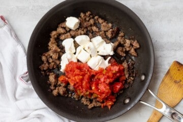 Browned sausage in skillet with Rotel Tomatoes and Cubed cream cheese.