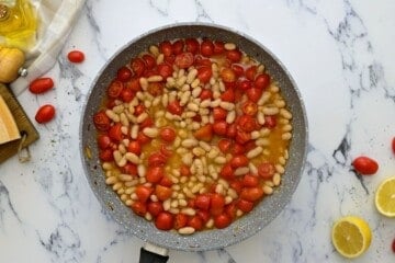 White beans and tomatoes together in saute pan.