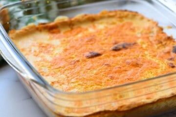 Baked taco dip with browned cheese in glass pan.