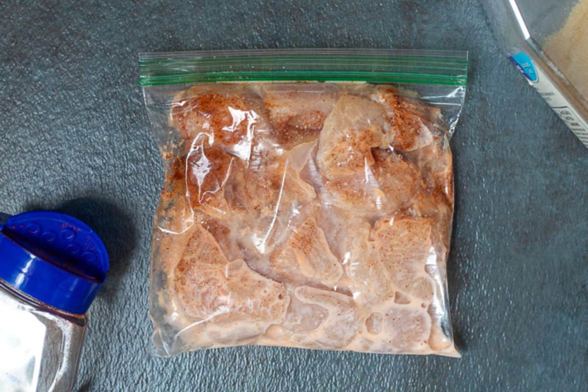marinated chicken in large freezer bag next to spices.