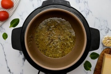 Broth in inner pot with garlic, oregano, and red pepper flakes sauteed in inner pot.