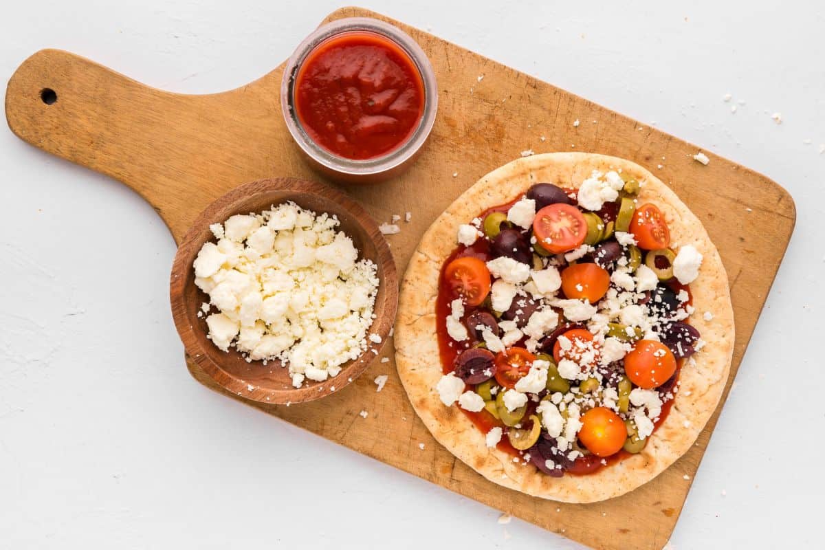 Assembled Pita Pizza topped with feta, olives, and tomatoes.
