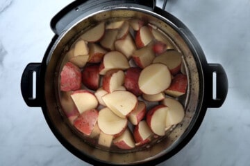 Red Potatoes with broth and salt inside inner pot of pressure cooker.