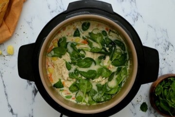 Instant Pot filled with creamy chicken gnocchi soup topped with fresh spinach.
