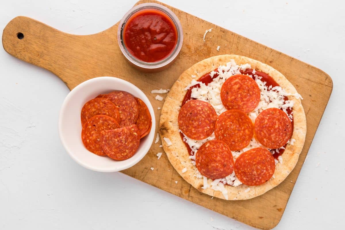 Assembled Pita Pizza topped with cheese, pizza sauce, and pepperoni.