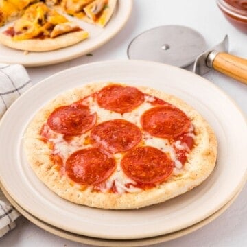 Pepperoni Pita Pizza on plate with other varieties of pita bread pizza in background.