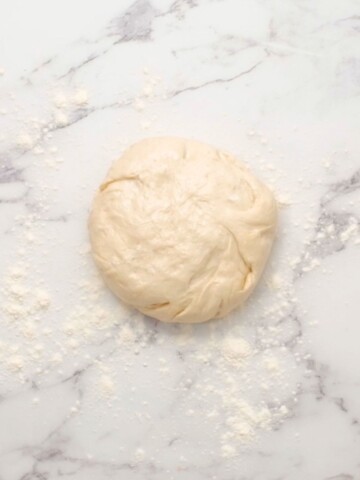 Pizza Dough in ball on floured surface.