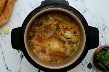 Inner pot with poached chicken in broth for gnocchi soup.