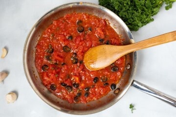 Puttanesca sauce with olives and capers in saute pan.