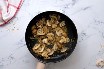 Sauteed chopped onions and sliced mushrooms in butter and olive oil for rice pilaf in saucepan.