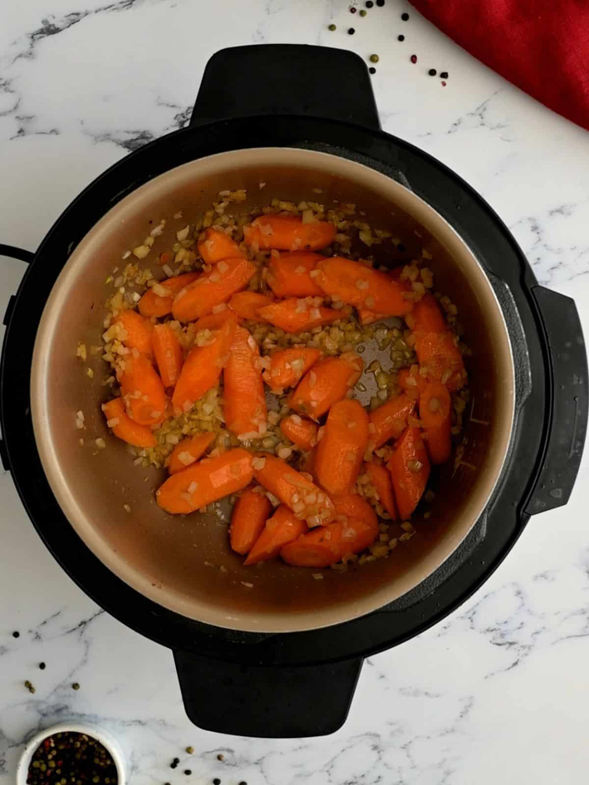 Carrots and onions sauteed in inner pot of Instant Pot.