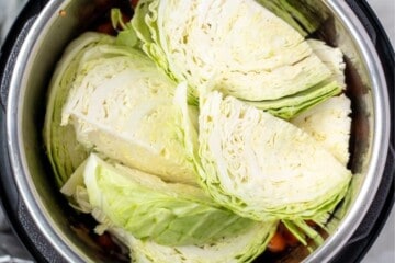 Potatoes, cabbage, and corn layered inside instant pot.