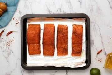 Four Salmon fillets with spice rub on lined sheet pan.