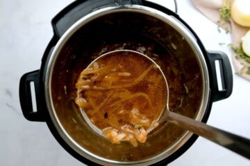 Ladle of onion soup coming out of inner pot.