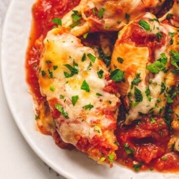 Stuffed Italian shells served on white plate topped with minced parsley.