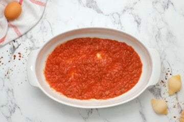 Spaghetti Sauce spread out onto a thin layer in oval baking dish.