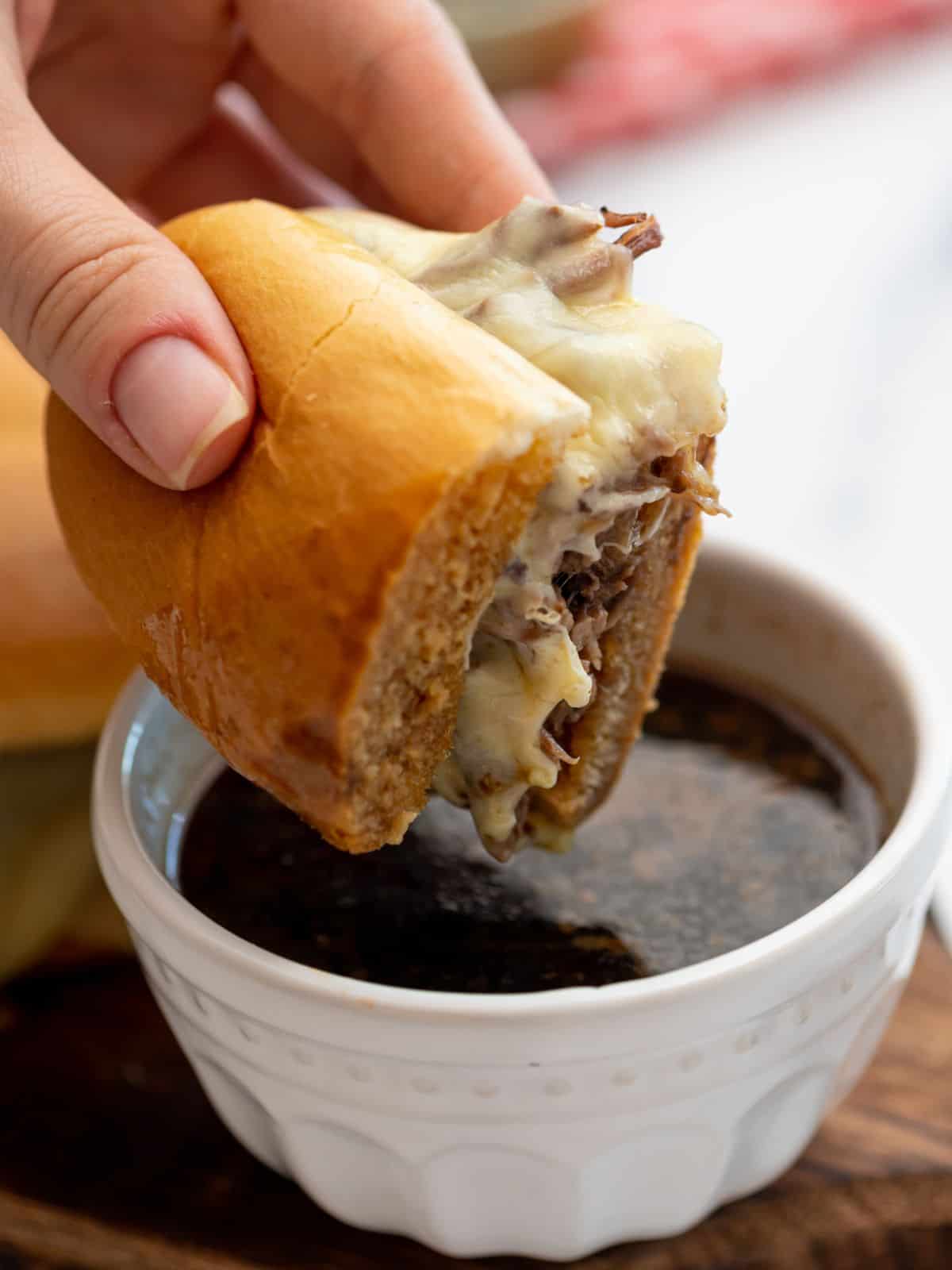 French Dip sandwich made with Instant Pot shredded beef being dipped into au jus.