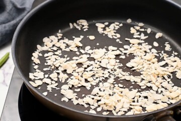 Slivered almonds in saute pan being toasted.