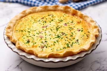 Baked Quiche in pie plate topped with chopped chives.