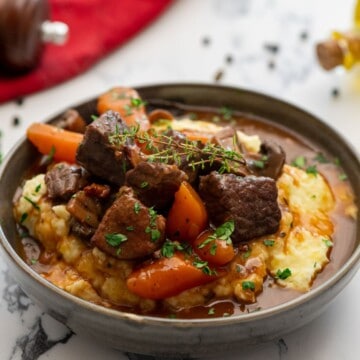 Bowl of Instant Pot Beef Bourguignon served over mashed potatoes.
