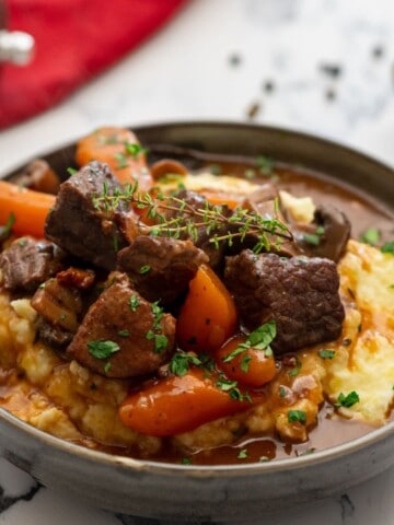 Bowl of Instant Pot Beef Bourguignon served over mashed potatoes.