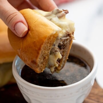 French Dip sandwich made with Instant Pot shredded beef being dipped into au jus.