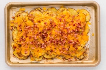 Irish Nachos on baking sheet topped with melted cheddar and bacon.