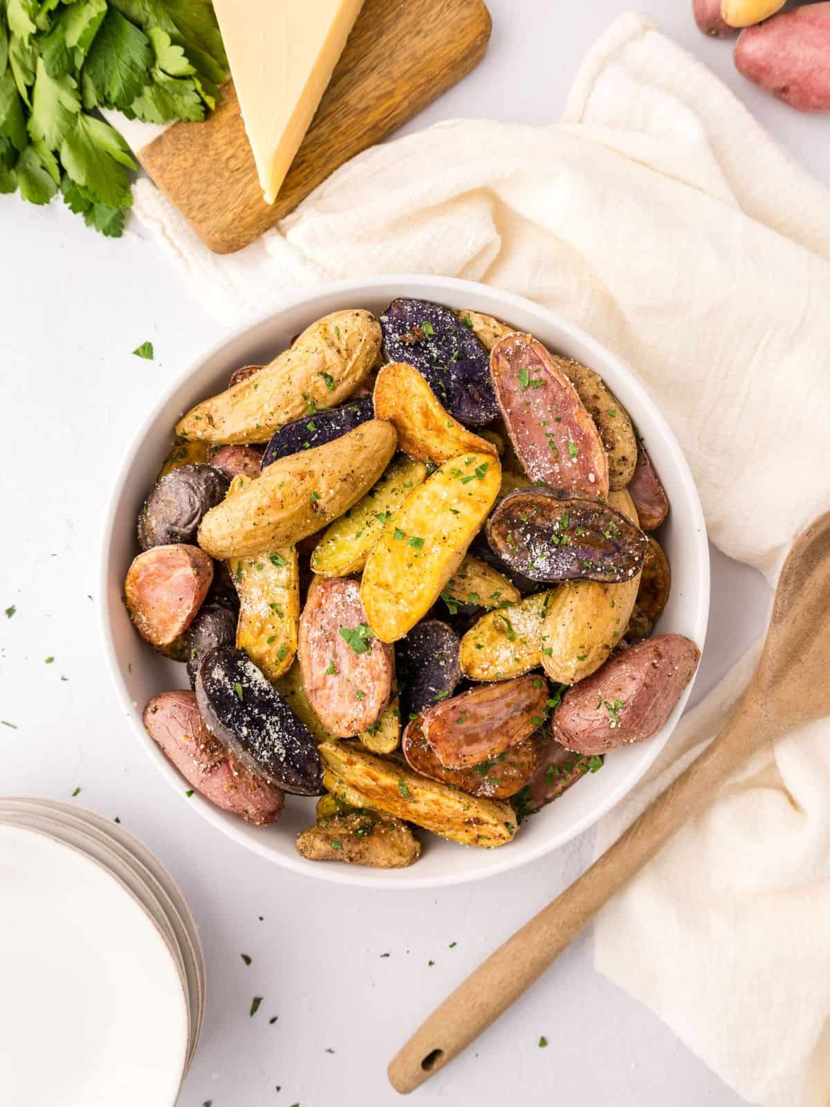 Bowl of fingerling potatoes topped with parmesan and parsley.