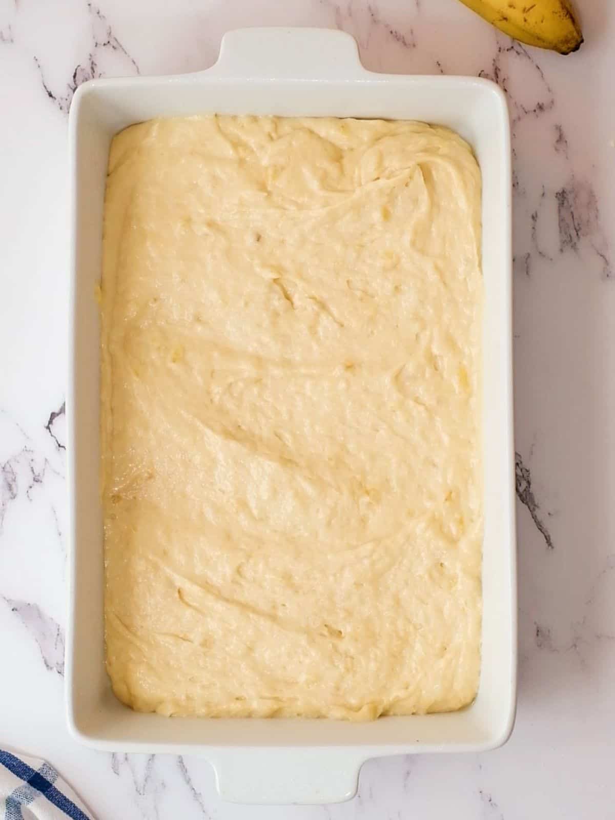 Banana Cake Batter spread out in a 9x13 white baking dish.