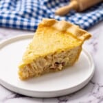 Slice of classic French Quiche Lorraine on white plate.