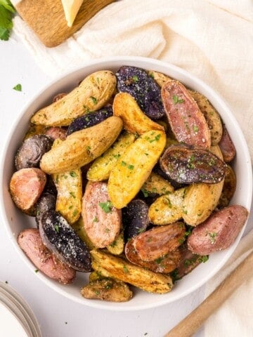 Bowl of fingerling potatoes topped with parmesan and parsley.