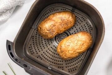 Air Fried crispy russet potatoes inside basket of air fryer.