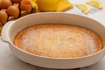 Baked Lemon Pudding in white baking dish topped with powdered sugar.