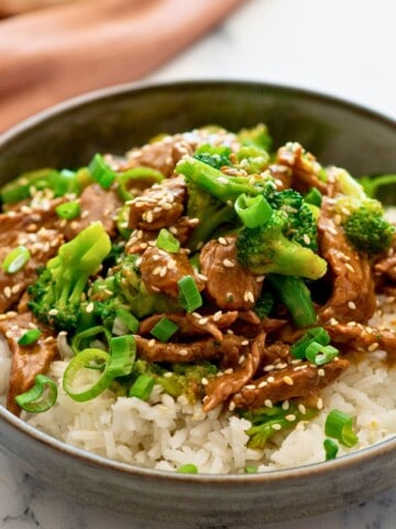 Instant Pot Beef and Broccoli served over white rice and topped with sesame seeds and sliced green onions.