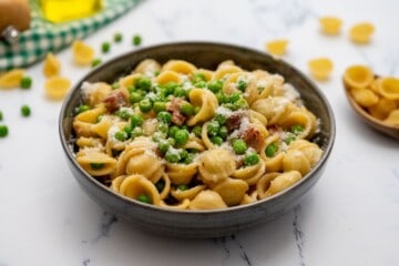 Bowl of pasta with peas, pancetta, and parmesan.