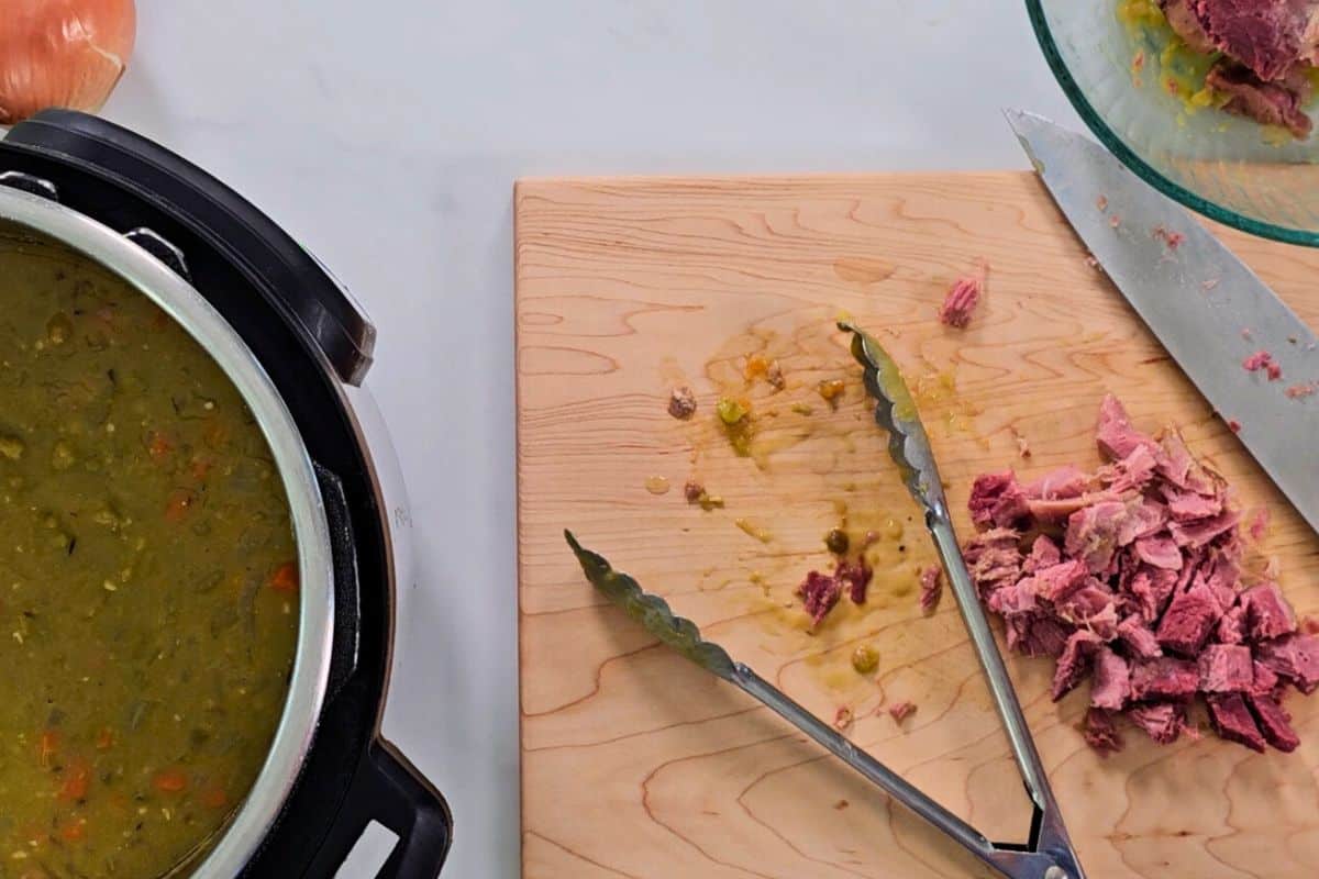 Split pea soup inside inner pot with diced ham on cutting board.