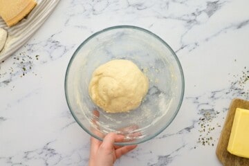 Breadstick dough in clear mixing bowl after dough pulls away from side of the bowl.