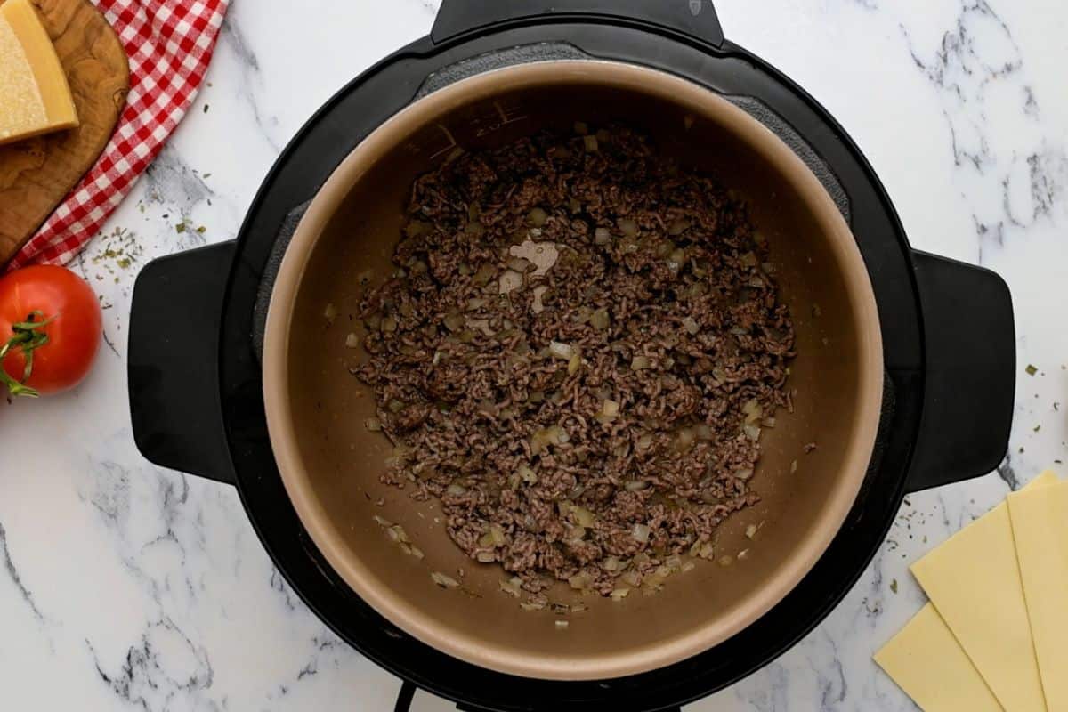 Ground beef sauteed in pressure cooker with minced onion.