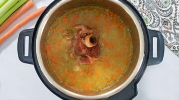 Instant Pot Filled with cooked split peas in a rich broth with ham bone in the inner pot.