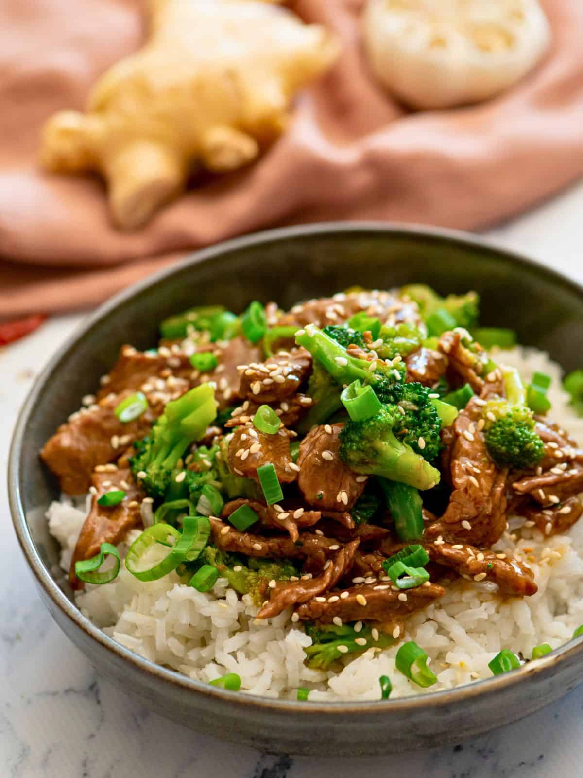 Instant Pot Beef and Broccoli served over white rice and topped with sesame seeds and sliced green onions.