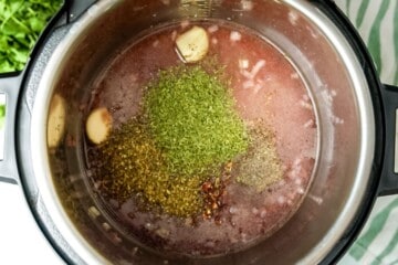 Onions, broth, wine, and seasonings layered inside inner pot.