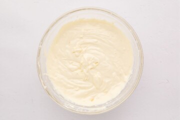 Cream cheese, sour cream, eggs, and lemon mixed together in mixing bowl.