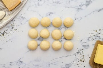 8 dough balls on floured surface before being shaped into breadsticks.