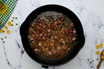 Pancetta and shallots in saute pan after being deglazed with white wine.