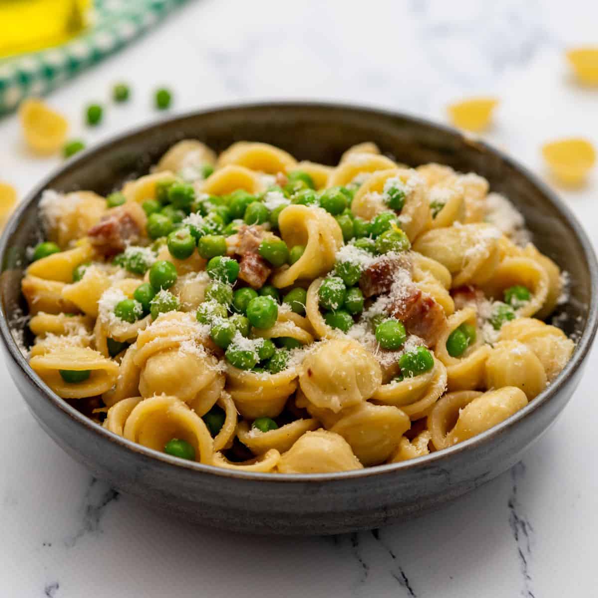 Bowl of pasta with peas, pancetta, and parmesan.