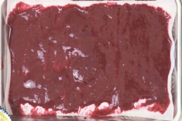 Homemade Fruit puree spread on parchment paper on rimmed baking sheet before drying it out.